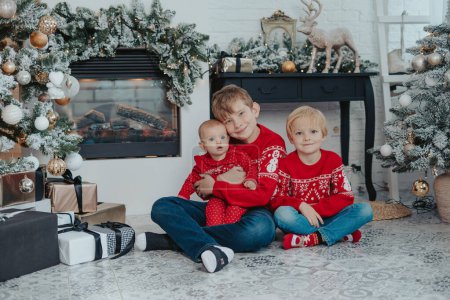 Photo for Happy family children brothers and sister smiling and sitting near fireplace. - Royalty Free Image