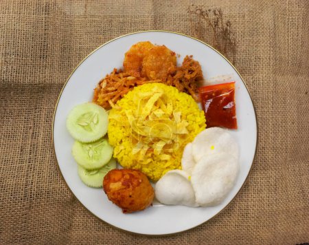 Téléchargez les photos : Nourriture traditionnelle indonésienne : Riz jaune avec des plats d'accompagnement oeuf épicé balado, concombre, omelette râpée, croustilles, bœuf râpé, chili sambal, craquelins - en image libre de droit