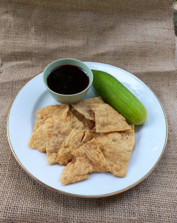 Photo for Crispy mpek mpek pempek fish skin deep fried served with cucumber and sour spicy vinegar sauce Indonesian traditional snack from Medan Sumatera - Royalty Free Image
