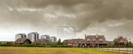 Photo for Panoramic view of the block of houses with reed roofs in Sventoji during the summer on cloudy day. Lithuania. - Royalty Free Image