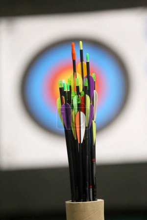 Téléchargez les photos : Arc de tir à l'arc sport fond. Flèches colorées devant la cible pour l'activité récréative de plein air - en image libre de droit