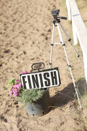 Téléchargez les photos : Terminer le panneau avec des fleurs à la ligne d'arrivée sur la piste de course de saut d'obstacles à l'extérieur - en image libre de droit