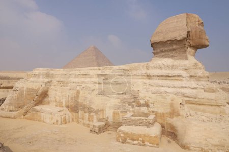 Foto de La esfinge con la gran pirámide asomándose detrás de su hombro. Giza Cairo Egipto África - Imagen libre de derechos