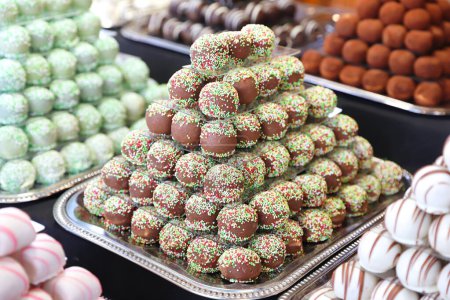 Foto de Los caramelos de mazapán de chocolate llenaron varios sabores. Bolas de dulzura construidas como una pirámide para sle en una pastelería - Imagen libre de derechos