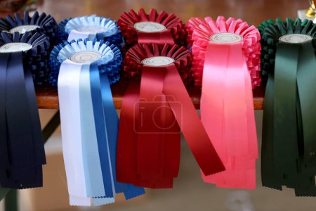 Foto de Grupo de hermosos trofeos coloridos y cintas para los ganadores y participantes en el evento ecuestre al aire libre caballo de carreras - Imagen libre de derechos