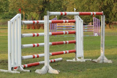 Show jumping poles obstacles, barriers, waiting for riders on show jumping training. Horse obstacle course outdoors summertime. Poles in the sand for equestrian event