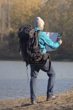 Téléchargez les photos : Portrait de voyageur homme au lac en automne avec une carte. Photo de haute qualité - en image libre de droit