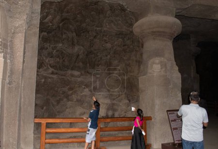 Foto de Cueva de elefantes, navi mumbai, India - 12 de agosto de 2023: turistas observando esculturas rupestres en la pared de la cueva - Imagen libre de derechos
