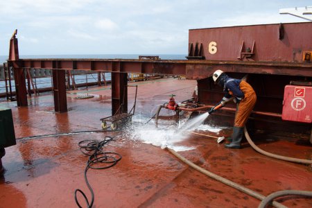 Photo for At sea - october 16, 2023 : ship's crew hosing down at cross deck of a cape size bulk carrier for deck cleaning purpose - Royalty Free Image