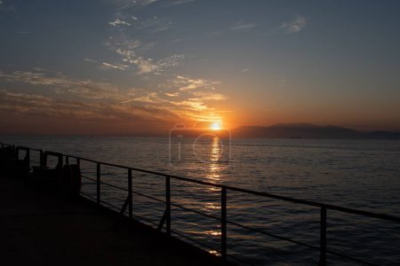 Blick auf den Sonnenuntergang über die Küste vom Deck eines Frachtschiffs