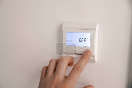 Photo for White thermostat for heating the warm electric floor and the boiler on the wall. the person turned off the finger control. information on the electronic display. - Royalty Free Image