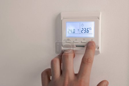 Photo for White thermostat for heating the warm electric floor and the boiler on the wall. the person turned off the finger control. information on the electronic display. - Royalty Free Image