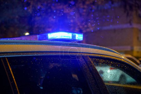 Blue lights of a police car with raindrops during a night