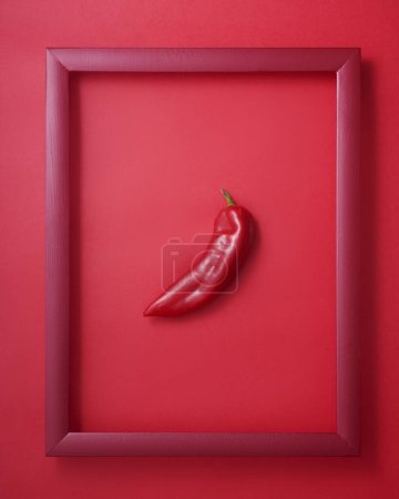 Photo for Whole red pepper in wooden picture frame on red background - Royalty Free Image