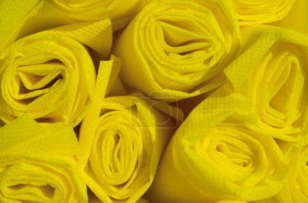 Foto de Rollos de tela no tejida de color amarillo oscuro con una textura áspera. bolsa spunbond de material de polipropileno industrial - Imagen libre de derechos