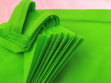 pile of green porous tote bags. non-woven fabric material. polypropiline bags on wooden planks