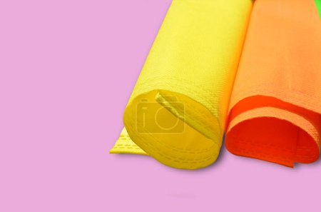 Foto de Rollo de tela no tejida amarilla y naranja sobre un fondo rosa y espacio de copia para texto - Imagen libre de derechos