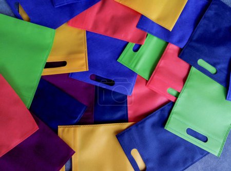 Foto de Colección de bolsas de colores pastel. hecho de polipropileno. pila de bolsas no tejidas con asas perforadas - Imagen libre de derechos