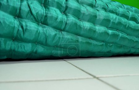 Foto de Un rollo de colchón de piso verde en el piso de cerámica blanca de la habitación - Imagen libre de derechos