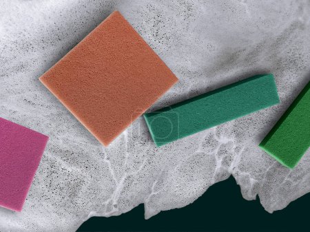 Foto de Cuatro coloridas esponjas de limpieza en la superficie del agua jabonosa - Imagen libre de derechos