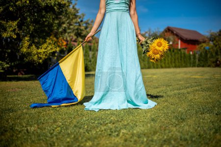 Téléchargez les photos : Patriotic Woman in Blue Dress Holding Ukraine Flag and Sunflowers, Advocating for Peace. Stop war - en image libre de droit