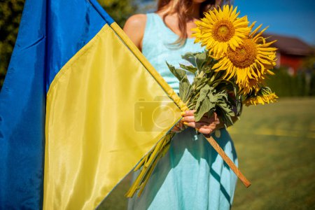 Téléchargez les photos : Patriotic Woman in Blue Dress Holding Ukraine Flag and Sunflowers, Advocating for Peace in world. Arrêtez la guerre - en image libre de droit