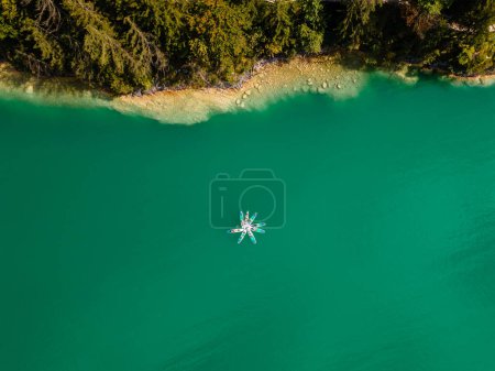 Photo for Connecting with Nature Top View of People Holding Hands on SUP Boards after Paddling in a Turquoise Alpine Lake - Royalty Free Image