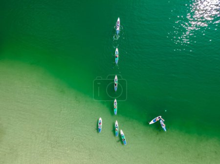Photo for Top View of People Paddling with Stand-Up Paddle Boards in Turquoise Water - Royalty Free Image