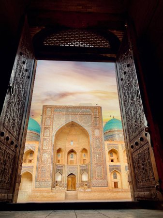 Téléchargez les photos : Coucher de soleil sur Mir i Arab madrassa à travers la vieille porte sculptée en bois, Boukhara, Ouzbékistan - en image libre de droit