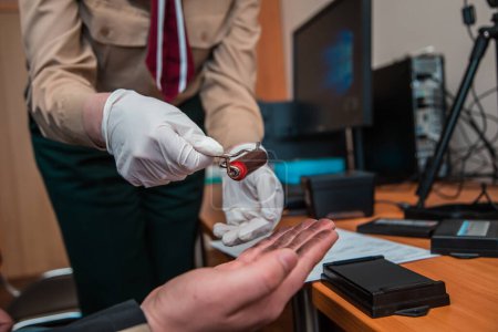 Foto de Experto forense toma de huellas dactilares para identificación con almohadilla de tinta y rodillo en el escritorio - Imagen libre de derechos
