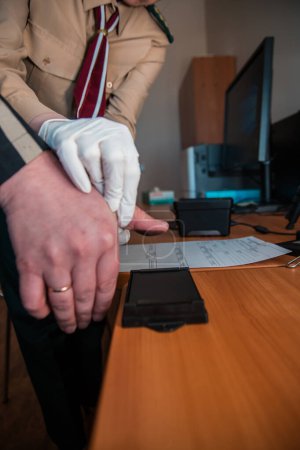 Foto de Experto forense toma de huellas dactilares para identificación con almohadilla de tinta y rodillo en el escritorio - Imagen libre de derechos