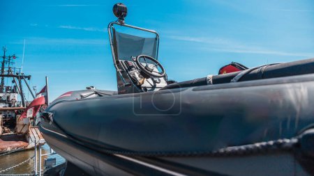 Photo for Close-up view of a military inflatable boat on the dock with ship cranes in the background under clear blue skies - Royalty Free Image