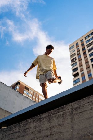 Photo for Young man stretching his legs before doing parkour tricks in the city. - Royalty Free Image