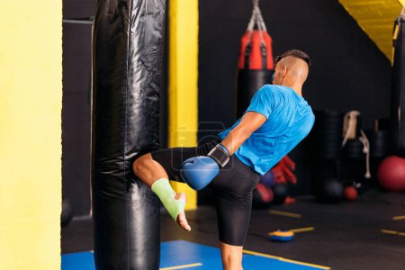 Photo for Kickboxing fighter performing Kicks with Knee on punching bag at the gym. Concept of kickboxing. - Royalty Free Image