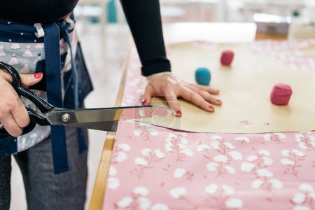 Foto de Costurera femenina no reconocida que trabaja en el taller de moda. Ella está cortando algunas telas coloridas. - Imagen libre de derechos