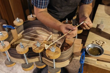 Foto de Luthier no reconocido creando una guitarra y utilizando herramientas en un taller tradicional. - Imagen libre de derechos