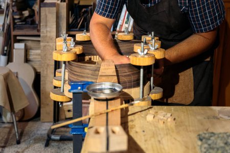 Téléchargez les photos : Un artisan méconnu crée une guitare et utilise des outils dans un atelier traditionnel. - en image libre de droit