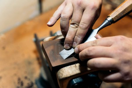 Téléchargez les photos : Artisan non reconnu utilisant des outils et travaillant dans son atelier traditionnel. - en image libre de droit