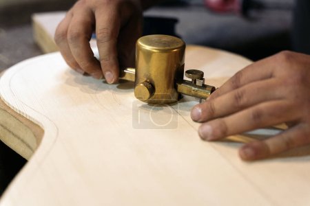 Photo for Unrecognized luthier in the process of making a guitar using tools in a traditional workshop. - Royalty Free Image