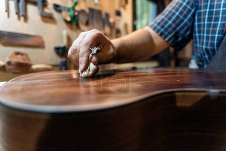 Téléchargez les photos : Luthier méconnu travaillant dans son atelier et faisant une guitare. Il utilise un produit spécial. - en image libre de droit