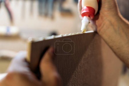 Foto de Luthier no reconocido trabajando en su taller y usando pegamento en una tabla de madera. - Imagen libre de derechos