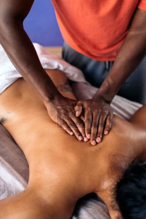 Photo for Unrecognized african american spa worker giving back massage to female client. - Royalty Free Image