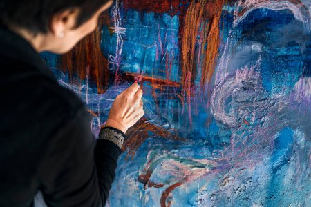 Foto de Pintora femenina no reconocida usando pintura azul en un lienzo grande. Ella está trabajando en su estudio de arte. - Imagen libre de derechos