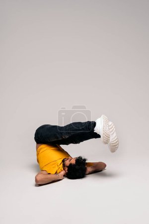 Foto de Bailarín masculino enérgico con ropa casual haciendo movimientos de hip hop en el estudio disparado contra fondo blanco. - Imagen libre de derechos