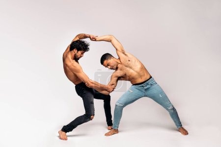 Photo for Shirtless dancers doing expressive dance performance in studio shot against grey background. They are barefoot. - Royalty Free Image