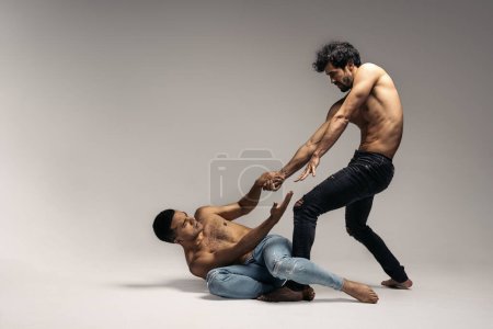 Photo for Shirtless dancers doing expressive dance performance in studio shot against grey background. They are barefoot. - Royalty Free Image