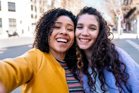 Photo for Beautiful young girls with curly hair smiling and taking selfie in the street. - Royalty Free Image