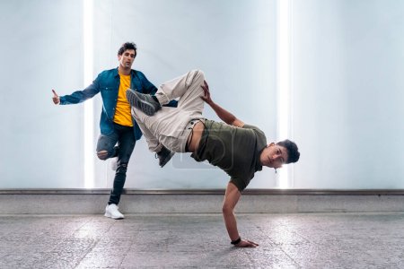 Photo for Two multi-ethnic friends dancing break dance and having fun against white wall with lights. - Royalty Free Image