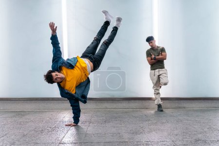 Photo for Two multi-ethnic friends dancing break dance and having fun against white wall with lights. - Royalty Free Image
