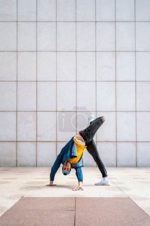 Photo for Cool dancer doing handstand in the street against white wall and looking at camera. - Royalty Free Image